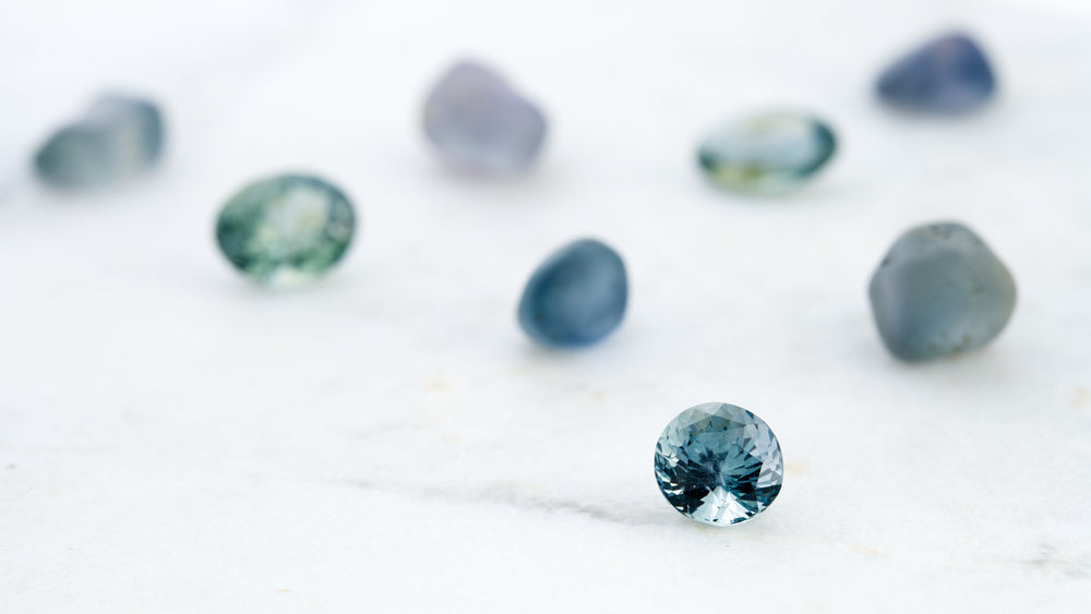 Blue gemstone on a white background with blurred gemstones around it